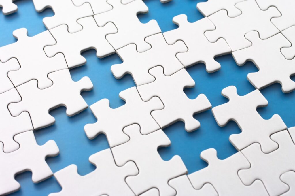 white puzzle with some pieces missing on light blue table